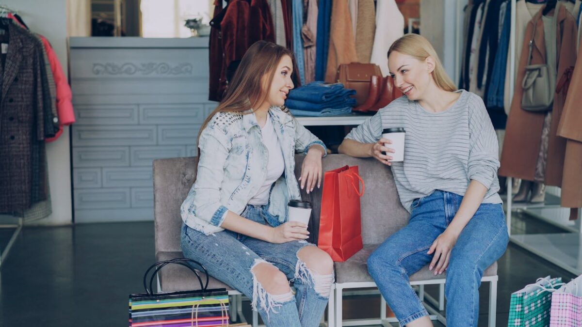 Two women share a coffee break while shopping in a boutique.